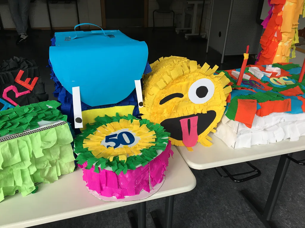 Bunte Piñatas auf einem Tisch, darunter eine mit der Zahl 50.
